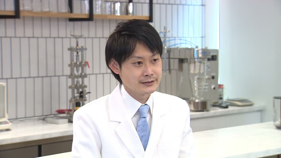 研究室で話す白衣の開発担当者