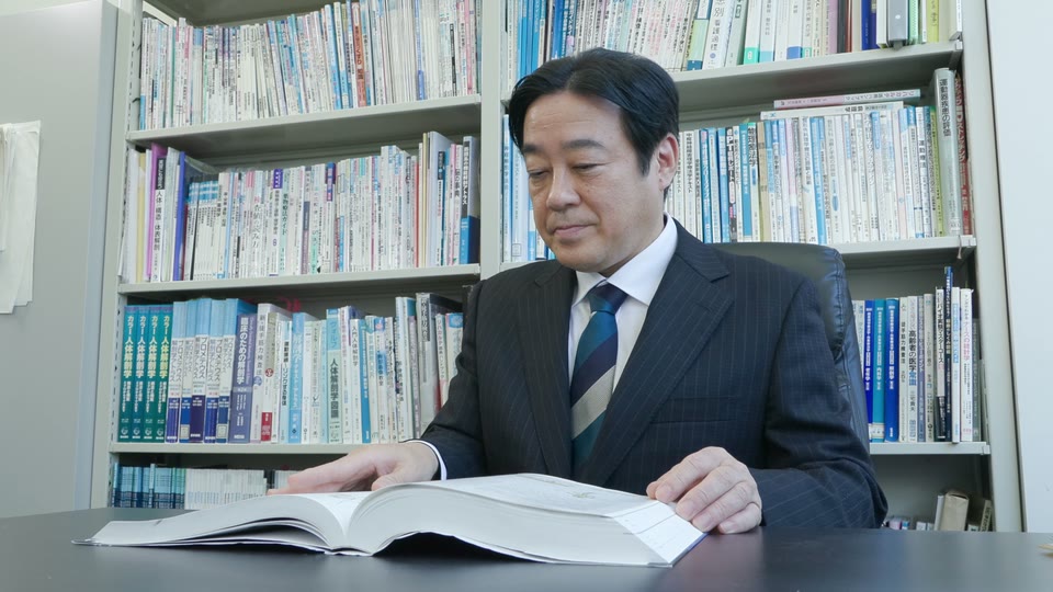 研究室で資料に目を通す神戸国際大学 南場芳文先生